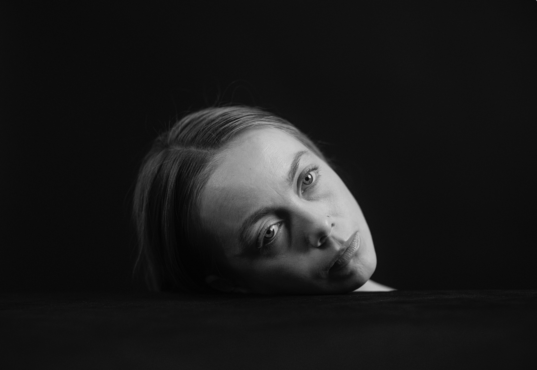 Black and white portrait of a head resting in darkness